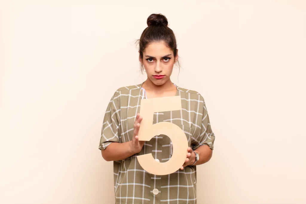 Person holding a large number five, wearing a checkered shirt.