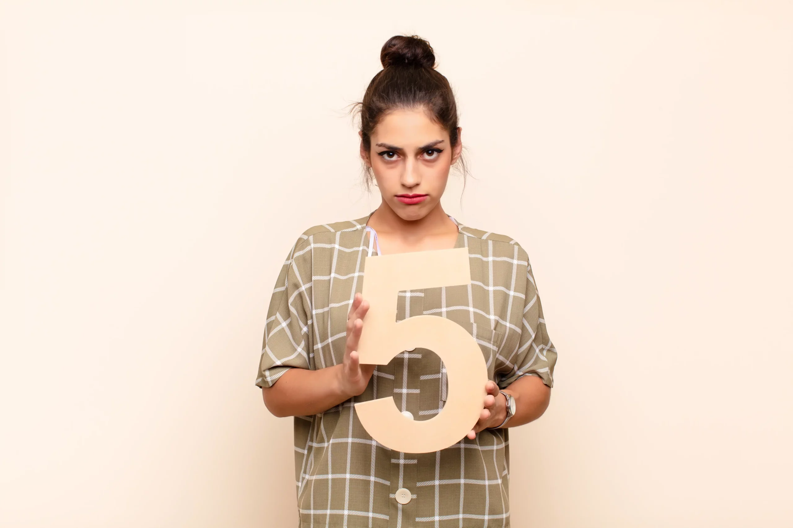Person holding a large number five, wearing a checkered shirt.