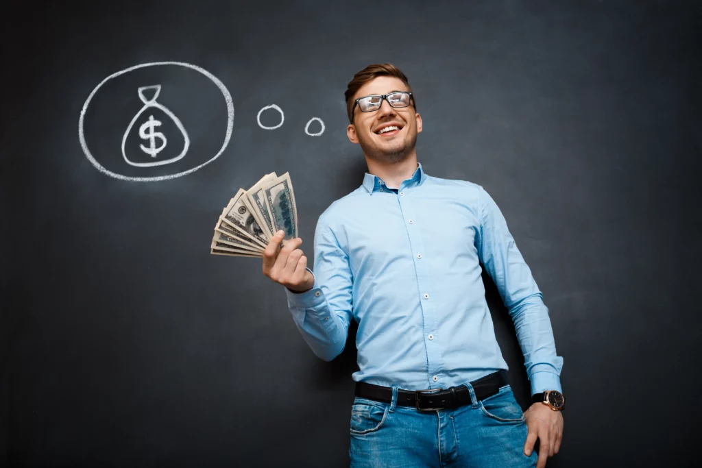 Smiling man holds cash beside a chalkboard drawing of a money bag.