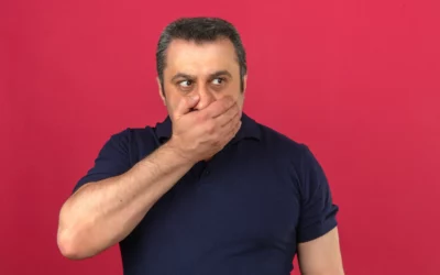 Man covering mouth reacting to strong burnt taste against solid red background